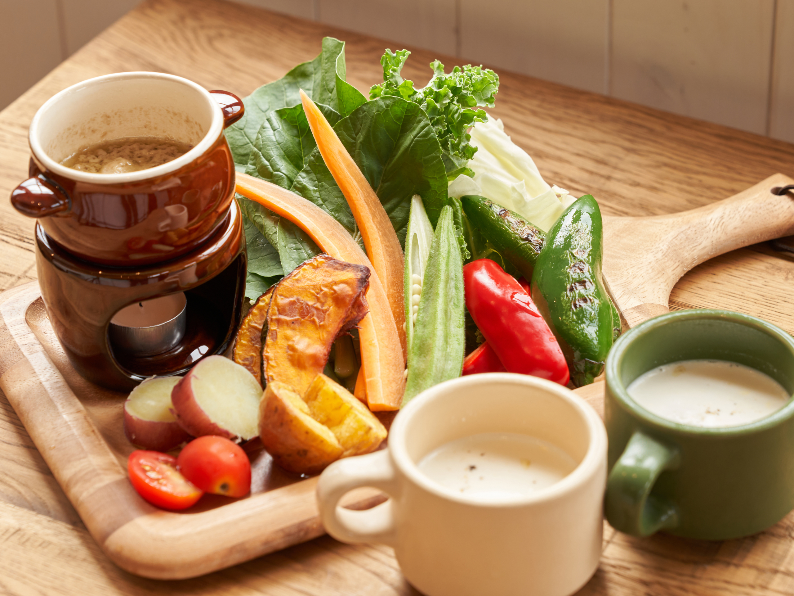 木のボードに彩り豊かな野菜とスープを並べた明るい料理写真